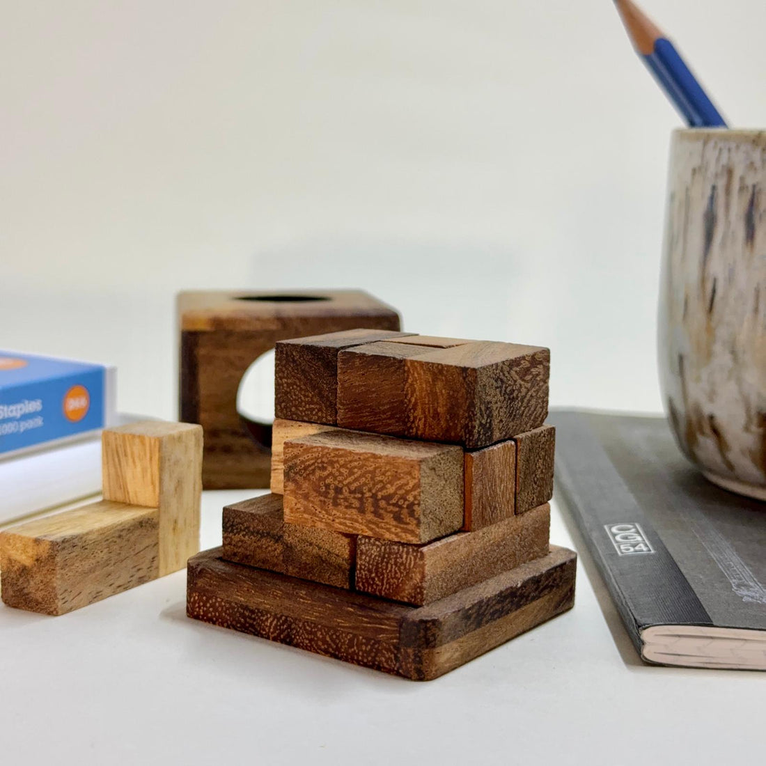 Wooden cube puzzle sitting on a table with stationery items.